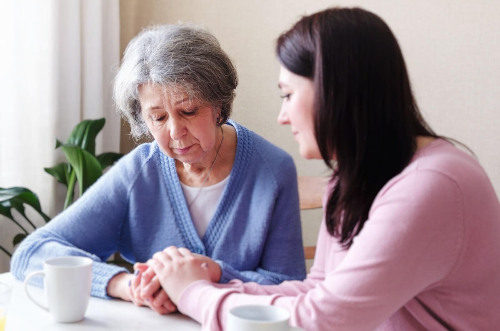 An adult child holding their ailing parent's hands as they address second thoughts about senior living.