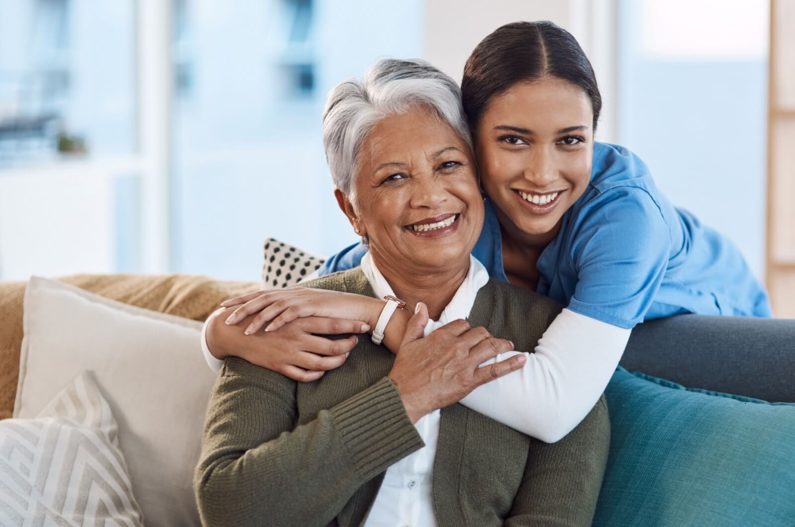 A smiling staff member in senior living embracing a happy older adult.