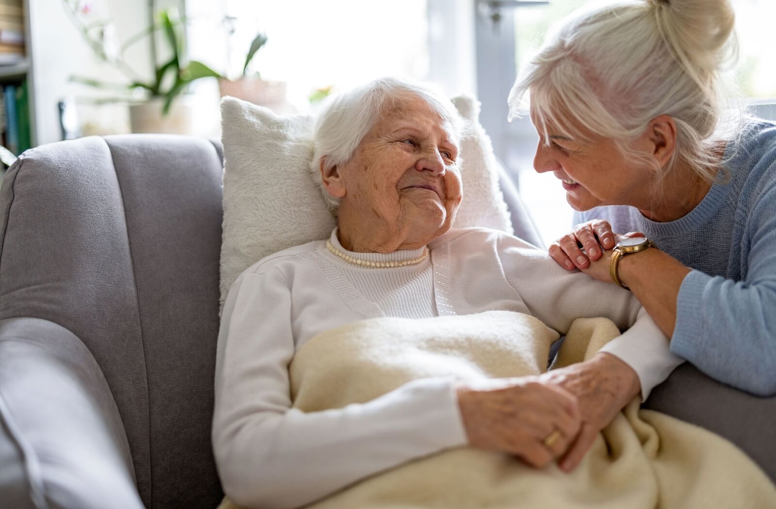 A smiling adult checks in on their senior parent, ensuring they have everything they need.