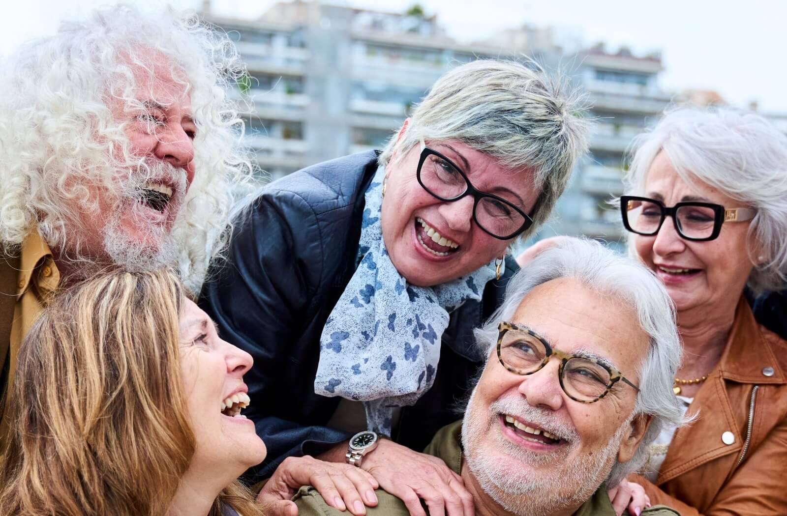 Group of joyful older adults laughing together outdoors enjoying meaningful connection in retirement.