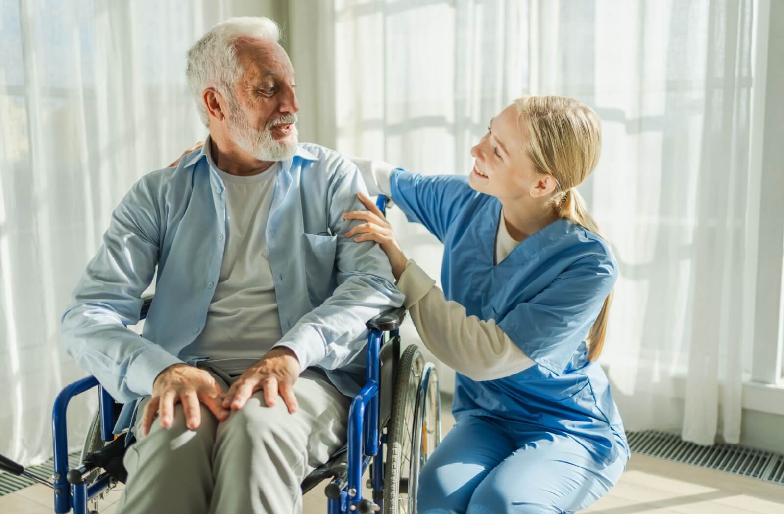 A nurse assists a senior in senior living who uses a wheelchair as a mobility aid to help prevent unnecessary falls
